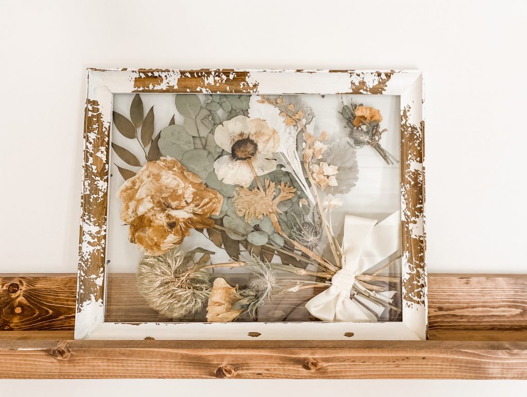 Pressed flowers in frame on wooden ledge