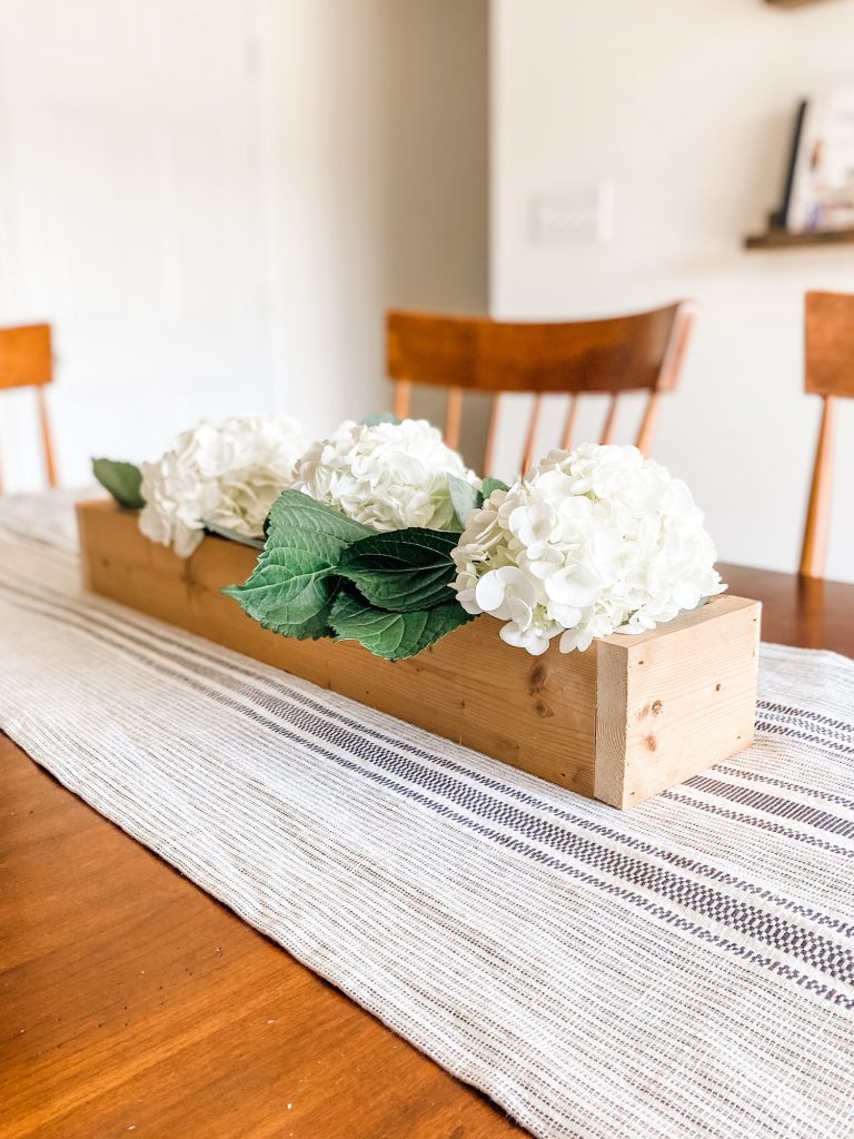 fresh flowers in a wooden rectangular box on a dining table
