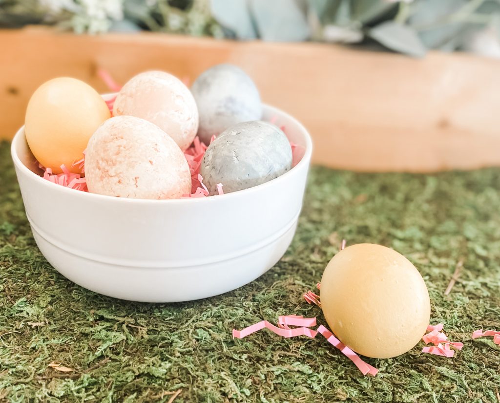 naturally dyed Easter eggs in bowl with pink paper on artificial grass