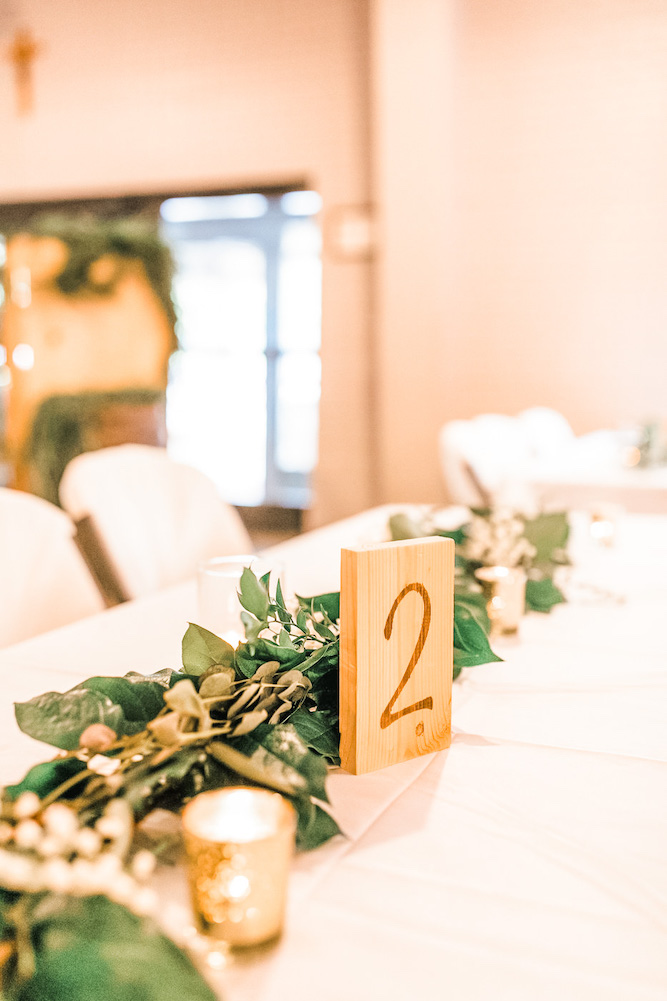Wooden raw table number 2 on table with greenery number and candles