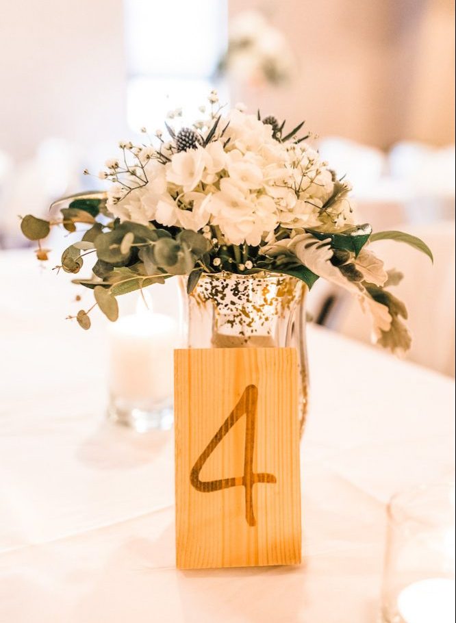 small block of raw wood with number 4 stained on it leaning up against a vase with florals in it bloombeautifullyco