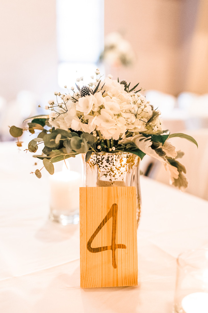 small block of raw wood with number 4 stained on it leaning up against a vase with florals in it bloombeautifullyco