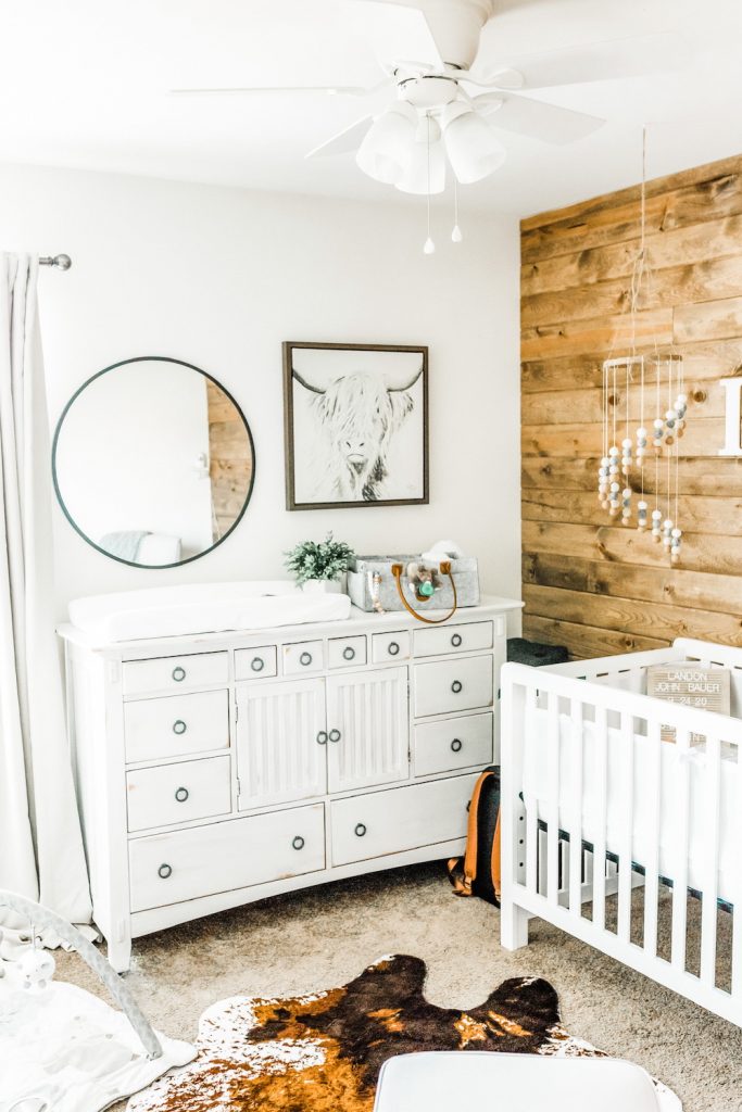 nursery room with white distressed dresser shown after being painted for rustic nursery