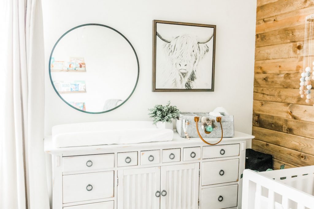 top half of chalk painted wood furniture piece with decor on top and wall decor above