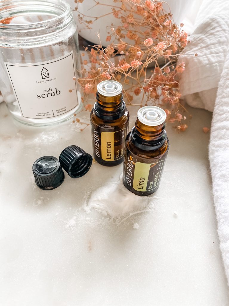 empty glass container with soft scrub label lemon and lime essential oils on white marble surface bloombeautifullyco