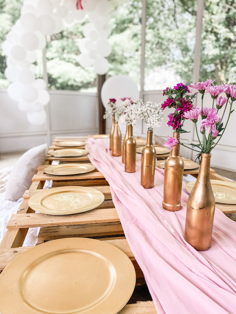 table on ground with pink and gold decor with trees in the background