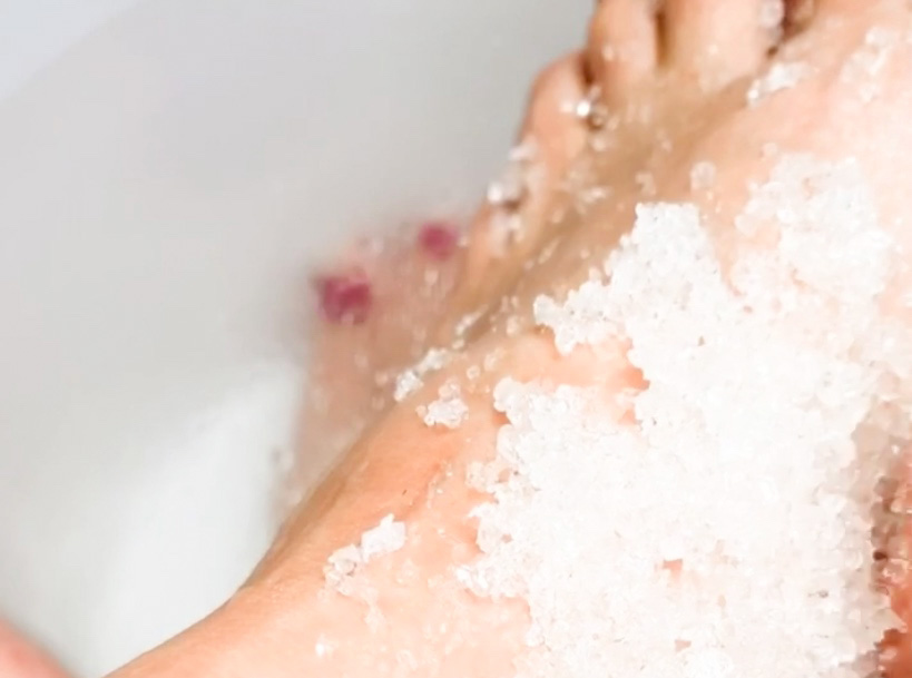 feet in a bath with white foot scrub on them