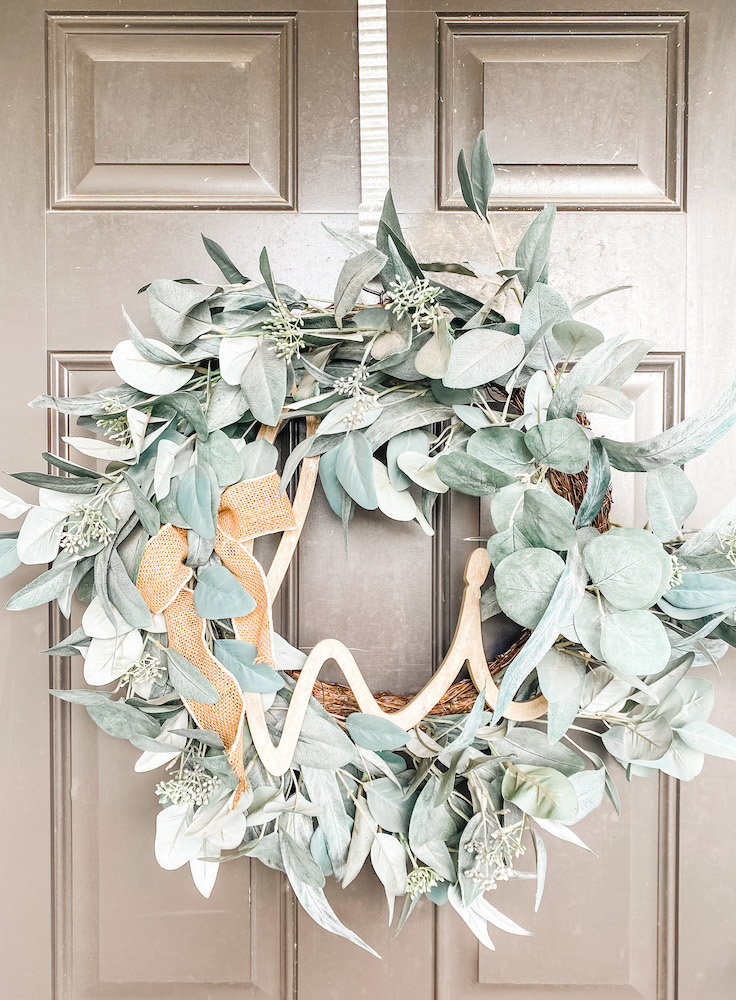 Faux eucalyptus wreath with hi sign and jute ribbon hanging on dark gray door