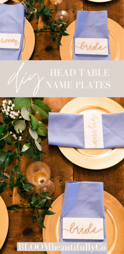 marble tiles with names laid on napkins and gold chargers all on a wood table with greenery Pin for Pinterest