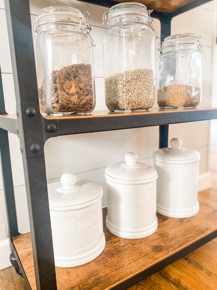 close up of clear containers with spices and white jars on a cart