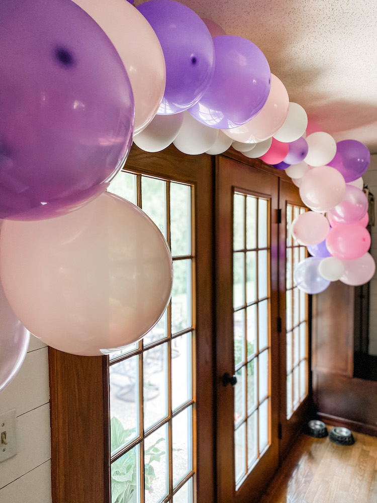 pink, purple, and white balloon garland hanging above French doors to outside