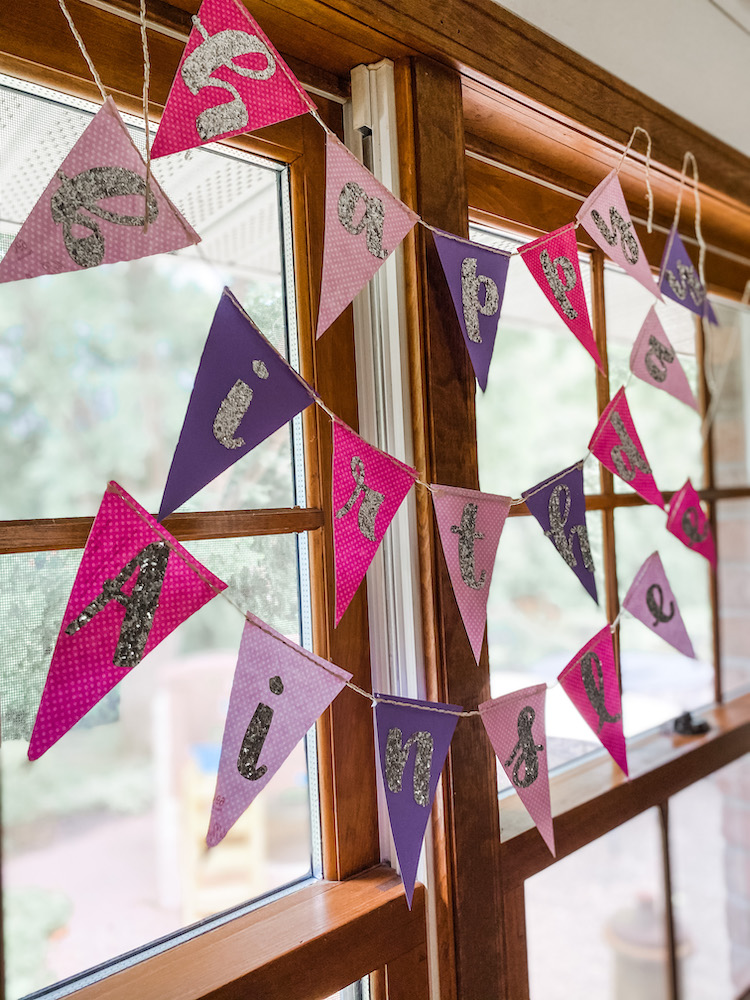 purple and pink happy birthday flag banner hanging on window