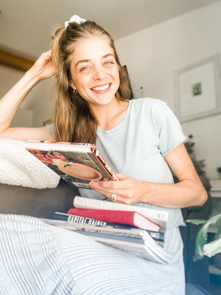 girl smiling while sitting down and holding a few different inspirational books