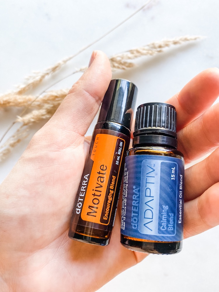 hand holding Doterra motivate roller blend oil and Doterra adaptive oil