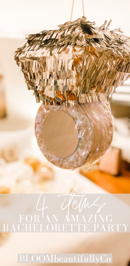 hanging ring piñata in the center of a room with a bed in the background with balloons on the bed with text 4 items for an amazing bachelorette party