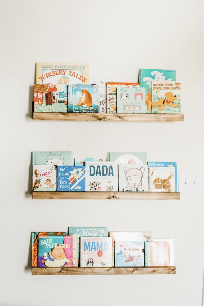 3 stained wood floating bookshelves with books on a white wall